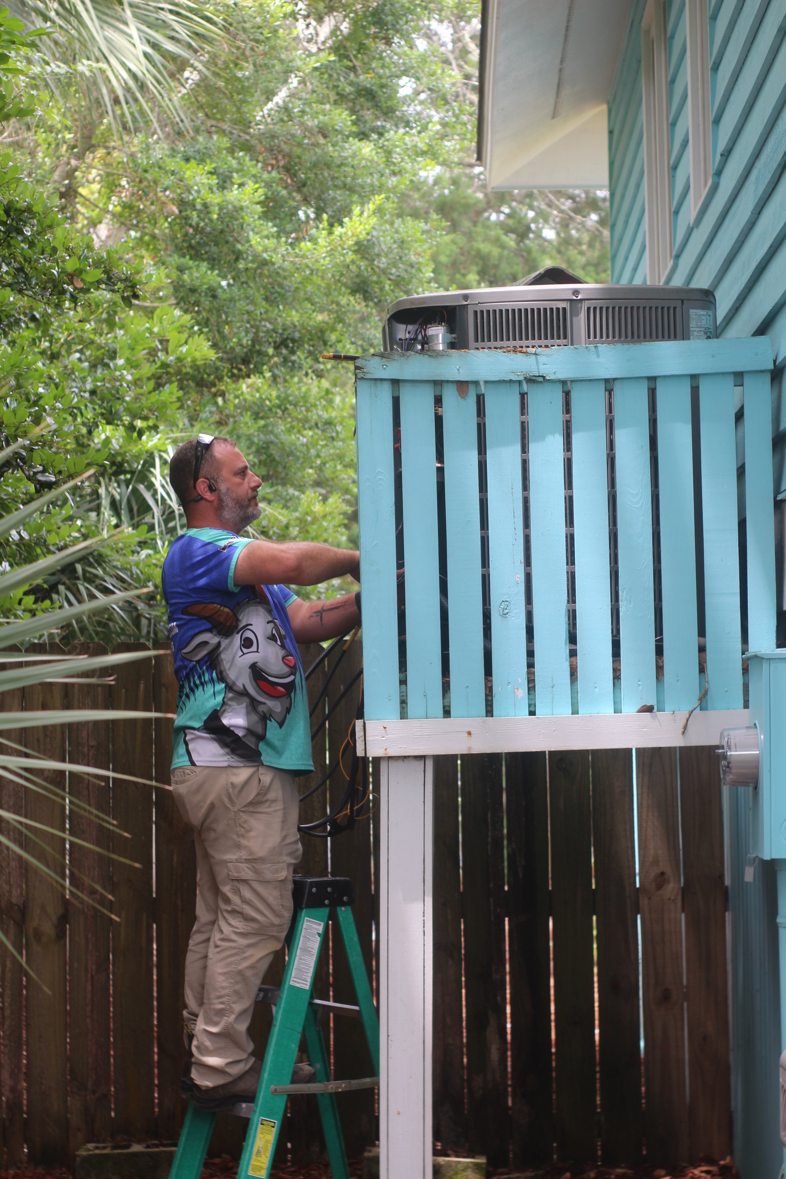 A Goat technician servicing an elevated outdoor unit