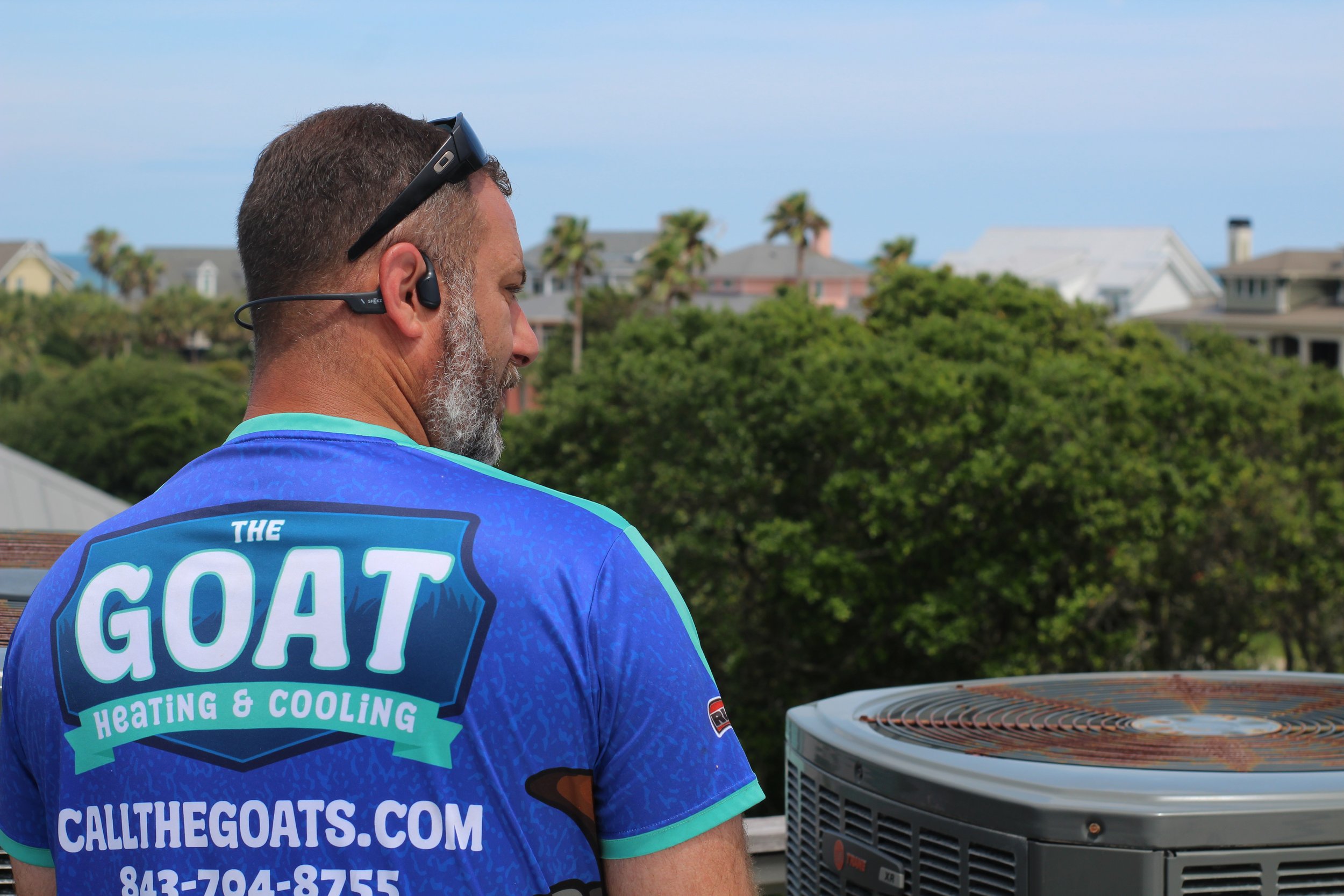 The Goat technician beside rooftop equipment